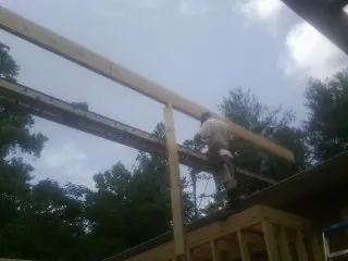 Carpenter setting a ridge beam over a new addition frame — Ice Dam Removal by Roofing Brothers in Keene