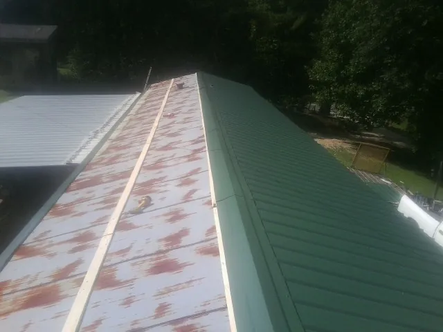 Old rusted panels beside newly installed green metal roofing — Wind Damage Roof Repair by Roofing Brothers in Keene