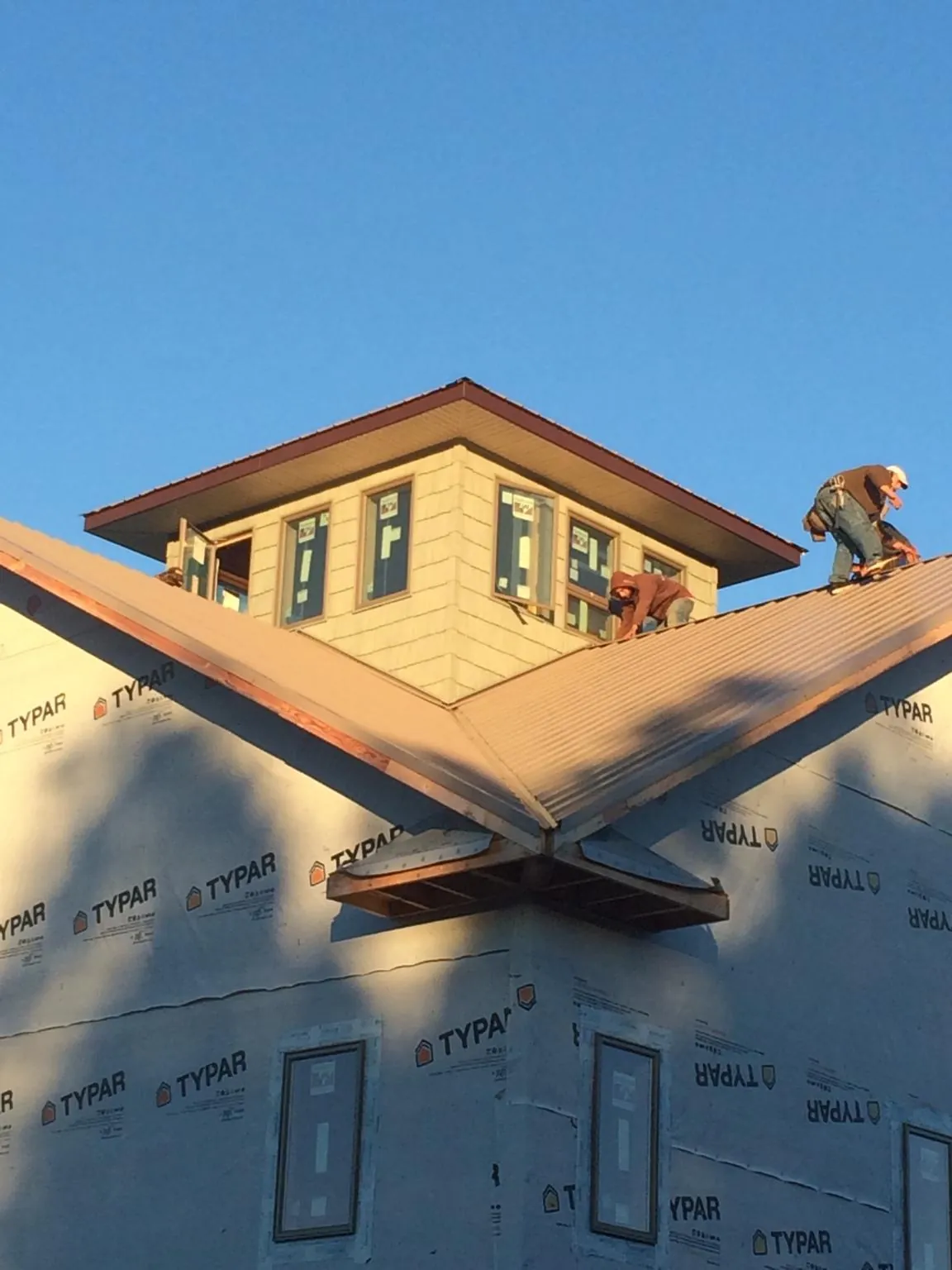 Roofers working around a rooftop cupola on a new metal roof at sunset — Roof Waterproofing in Keene by Roofing Brothers